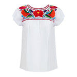 White short-sleeve blouse with colorful embroidered floral yoke in red, orange, purple, and blue, finished with zigzag trim."